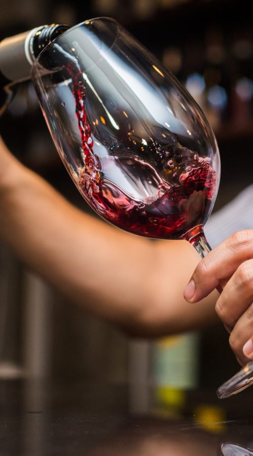 waiter-pouring-red-wine-in-a-glass-at-restaurant-scaled